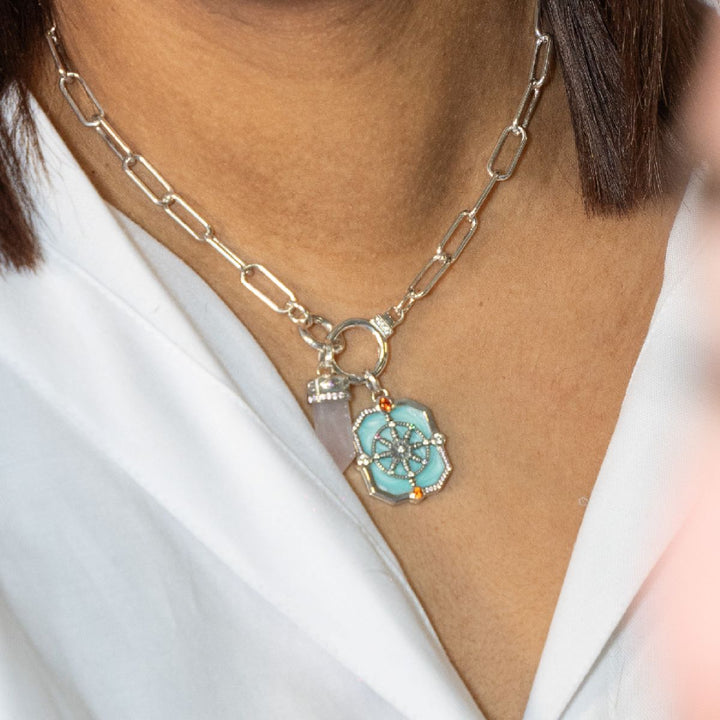 Sterling silver paperclip chain necklace with turquoise enamel Dharma wheel pendant and rose quartz crystal charm.