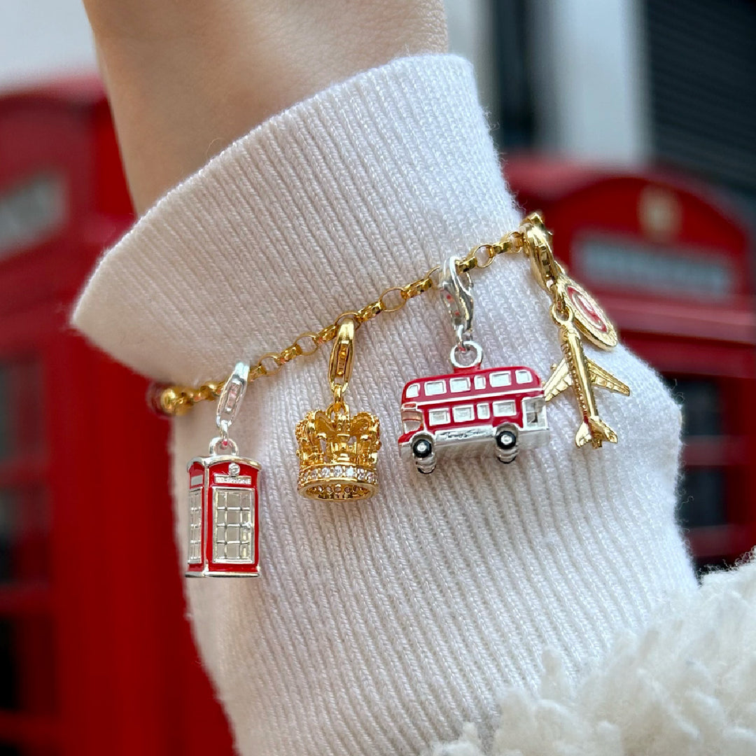 Gold-plated charm bracelet featuring colourful enamel charms: camera, cactus, heart, sunglasses, flip-flop, ice lolly, and palm tree.