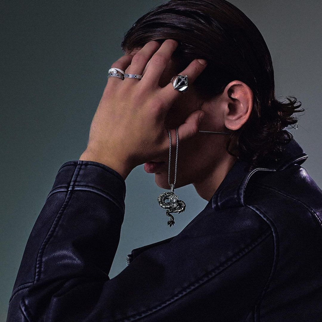 Woman seen from behind showcasing a THOMAS SABO crystal-pavé cross pendant necklace and silver bracelets, with dark hair and arm tattoo.