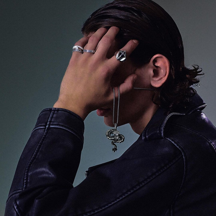 Woman seen from behind showcasing a THOMAS SABO crystal-pavé cross pendant necklace and silver bracelets, with dark hair and arm tattoo.