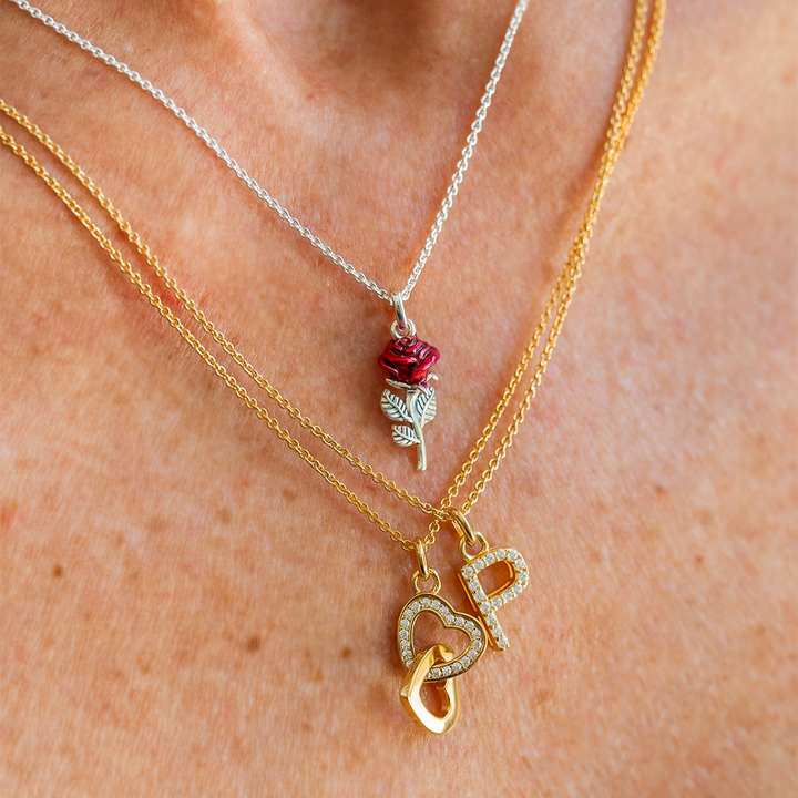 Woman seen from behind showcasing a THOMAS SABO crystal-pavé cross pendant necklace and silver bracelets, with dark hair and arm tattoo.