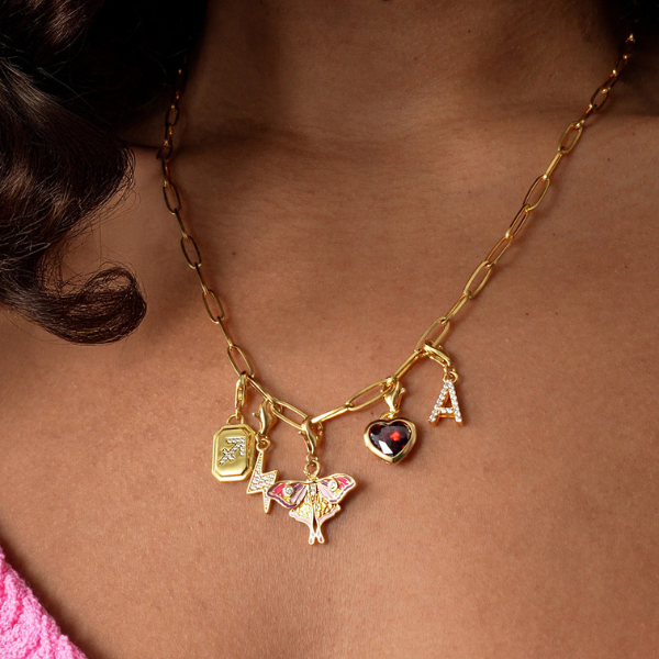 Two hands clasped together wearing THOMAS SABO yellow gold and sterling silver rings, bracelet, and crown pendant necklace; 
