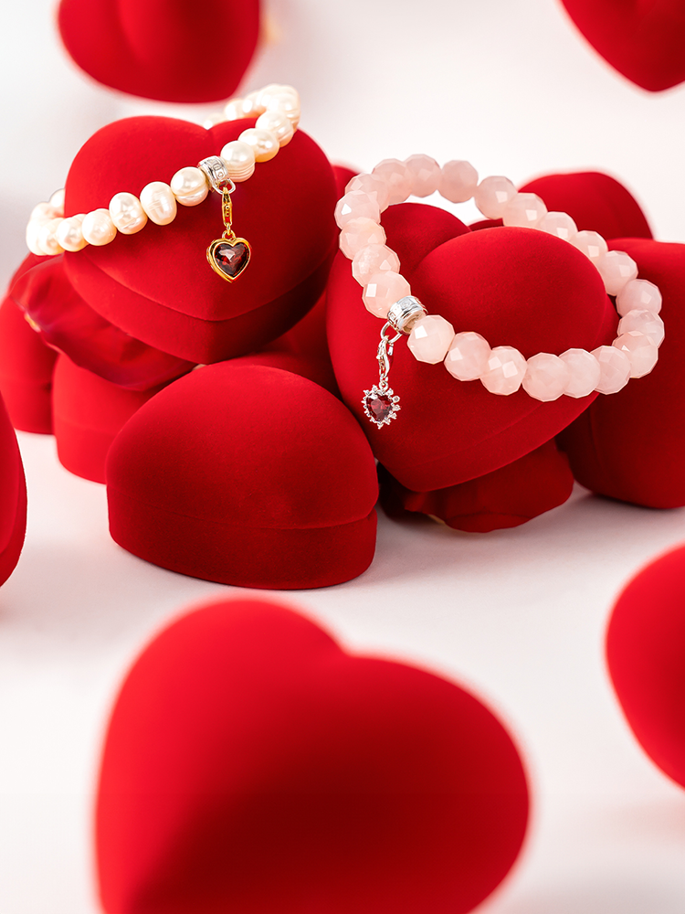 Two hands clasped together wearing THOMAS SABO yellow gold and sterling silver rings, bracelet, and crown pendant necklace; "Together" campaign.